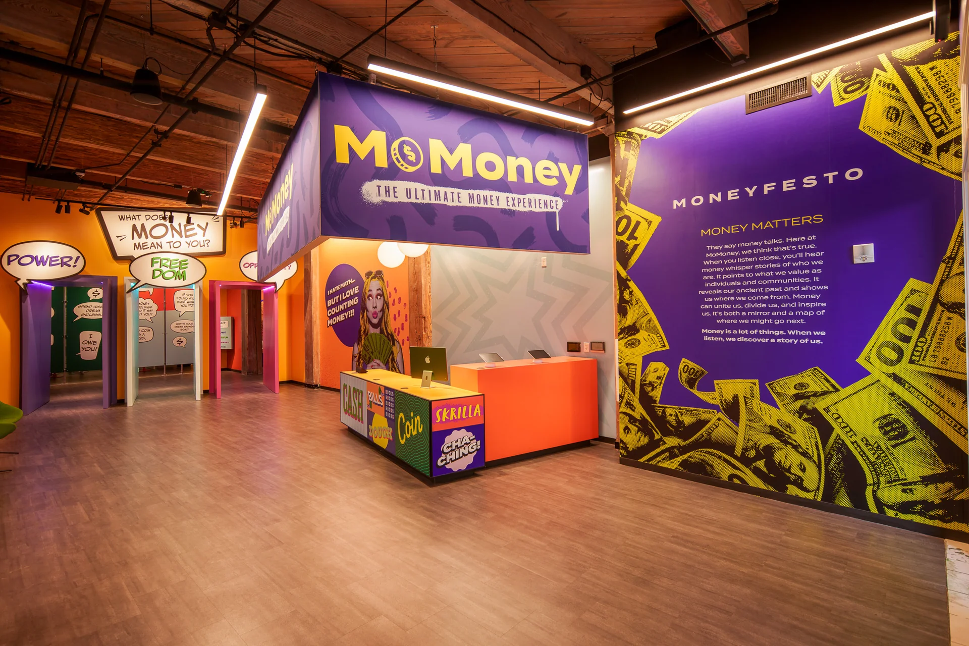 钱币实验馆's lobby: purple signage above an orange reception desk, with speech-bubble doorways and the Moneyfesto wall.