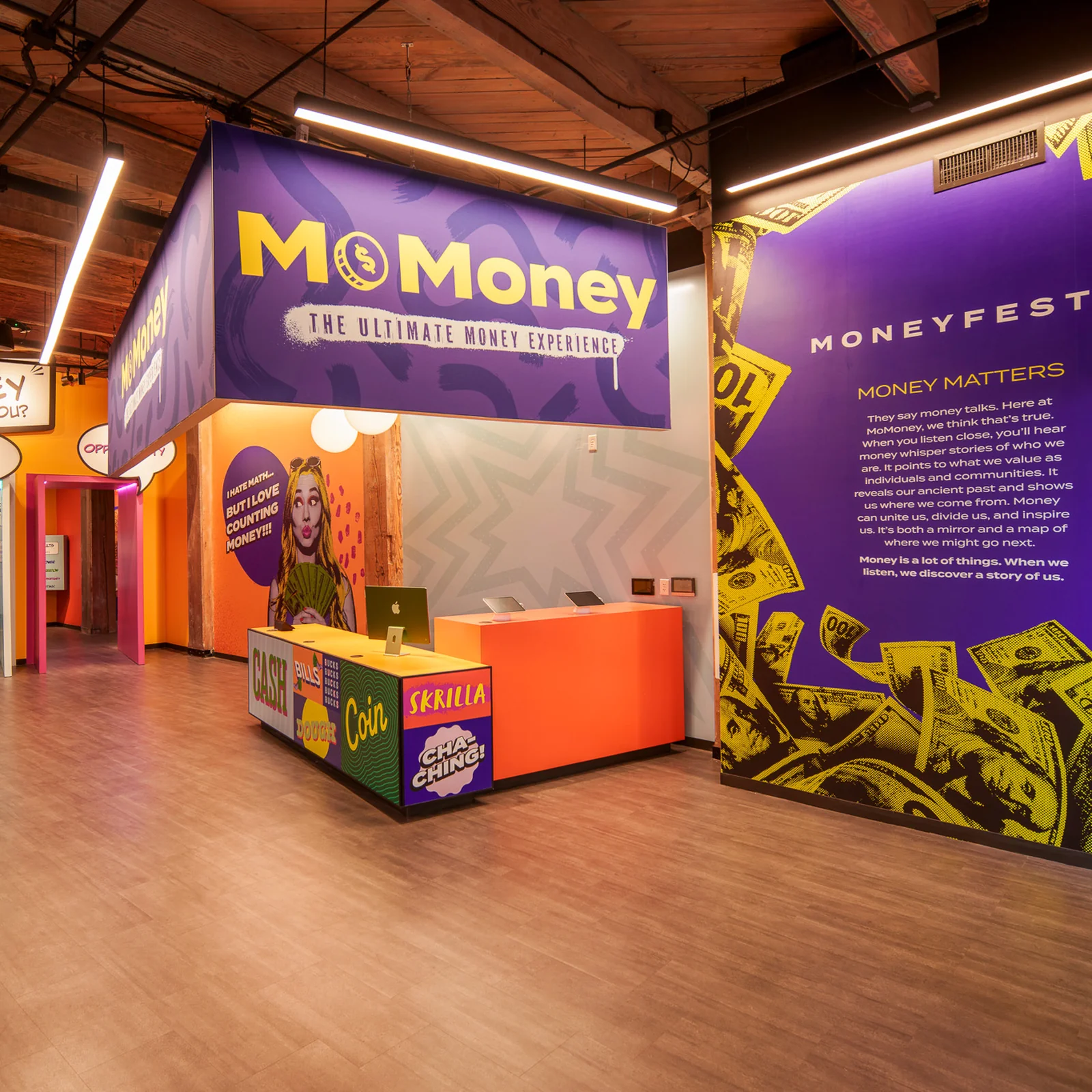 钱币实验馆's lobby: purple signage above an orange reception desk, with speech-bubble doorways and the Moneyfesto wall.